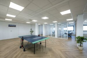 Moderne kantoorruimte aan de Joan Muyskenweg met glazen vergaderruimtes, een tafeltennistafel en houten visgraatvloer.